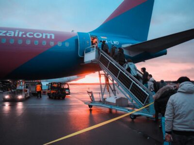 טיסות הכי זולות Passengers boarding an airplane at sunset with a vivid sky in the background, capturing a travel moment.