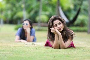 Young women enjoying a sunny day at a park in Bengaluru, India, lying on the grass and posing naturally.