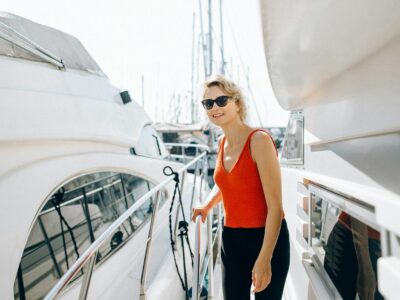 טיסות נופש A woman in sunglasses stands on a yacht, enjoying a sunny day outdoors.
