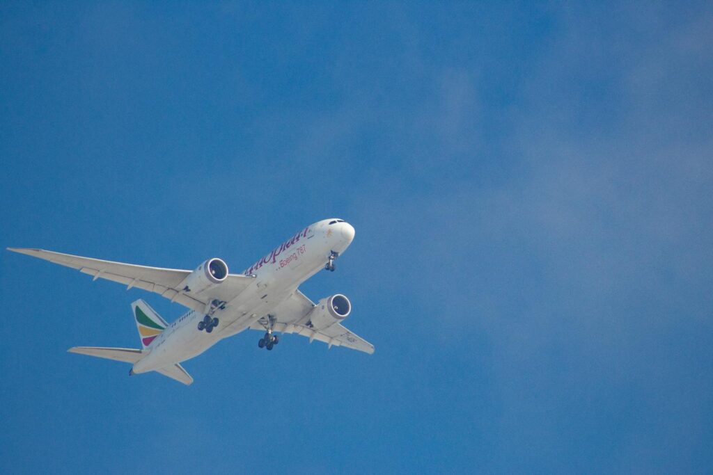 A commercial airplane flying overhead with clear blue skies as the backdrop.